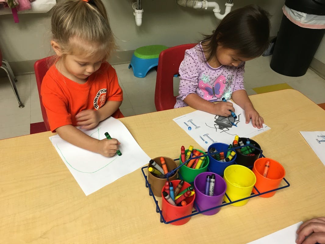 Two children coloring at a table with crayons