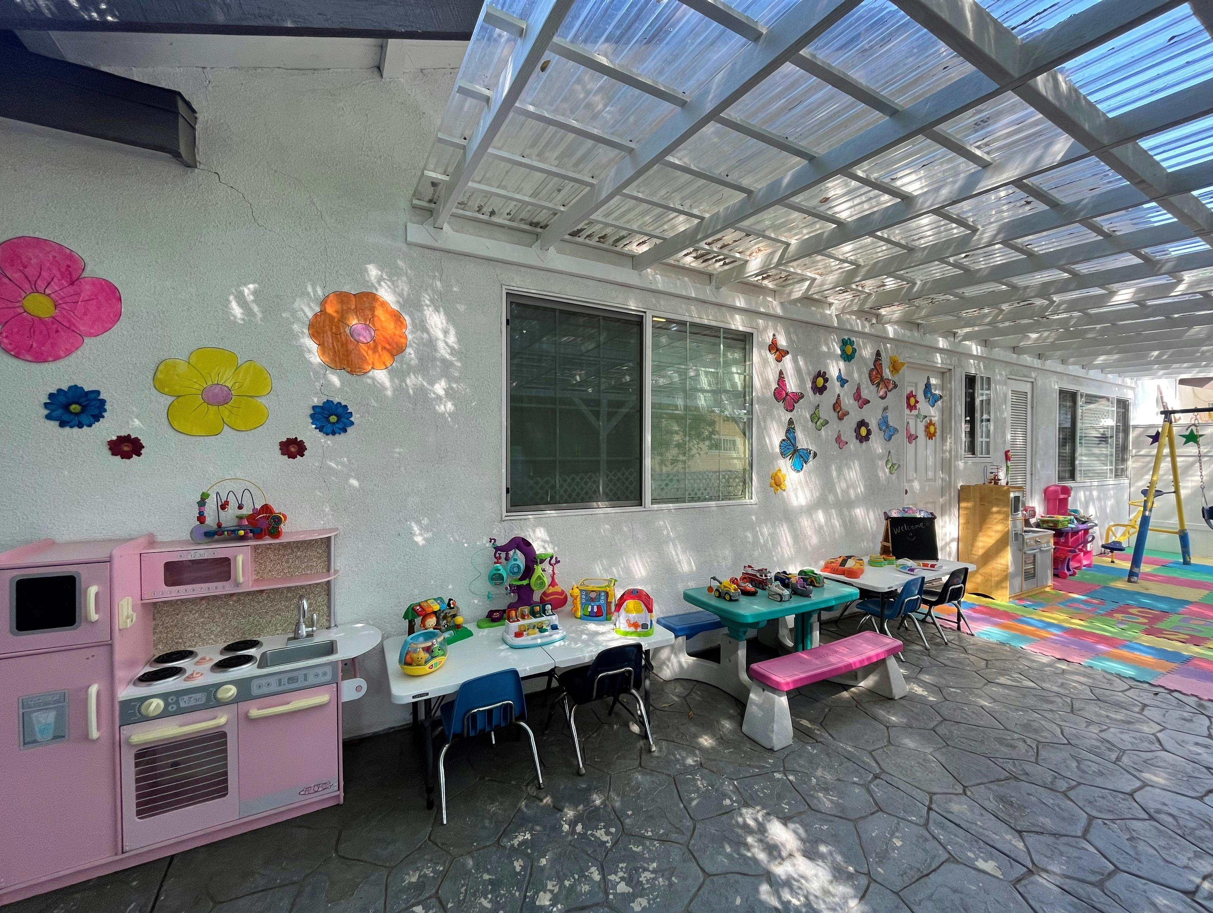 Outdoor play area with small tables, chairs, and a toy kitchen