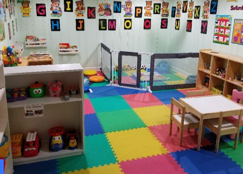 Playroom with colorful floor mats, small table and chairs, and shelves with toys