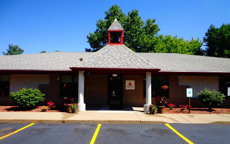 Entrance of a building with a red steeple on the roof and a sign for KinderCare