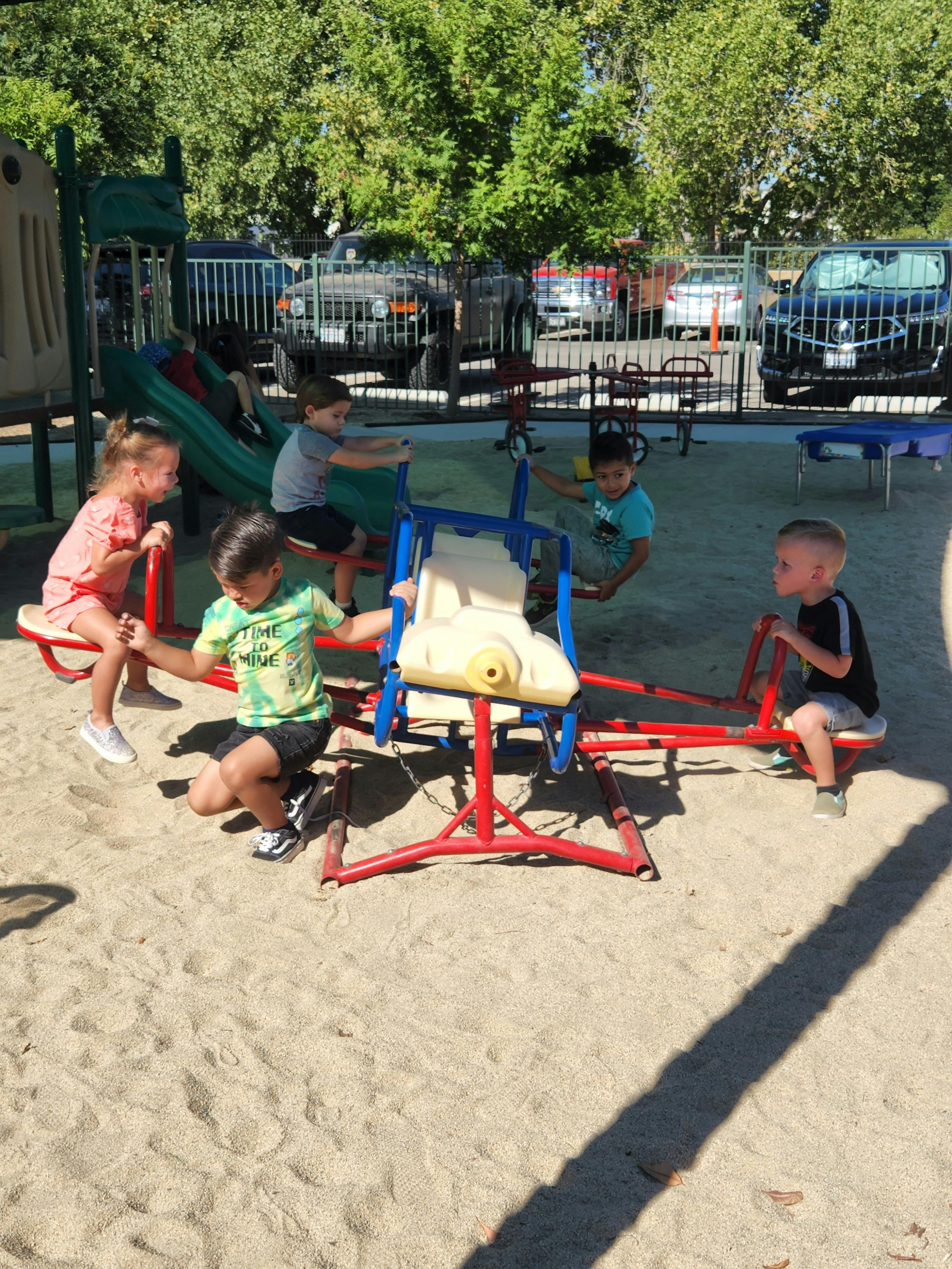 Children playing on a seesaw and other playground equipment