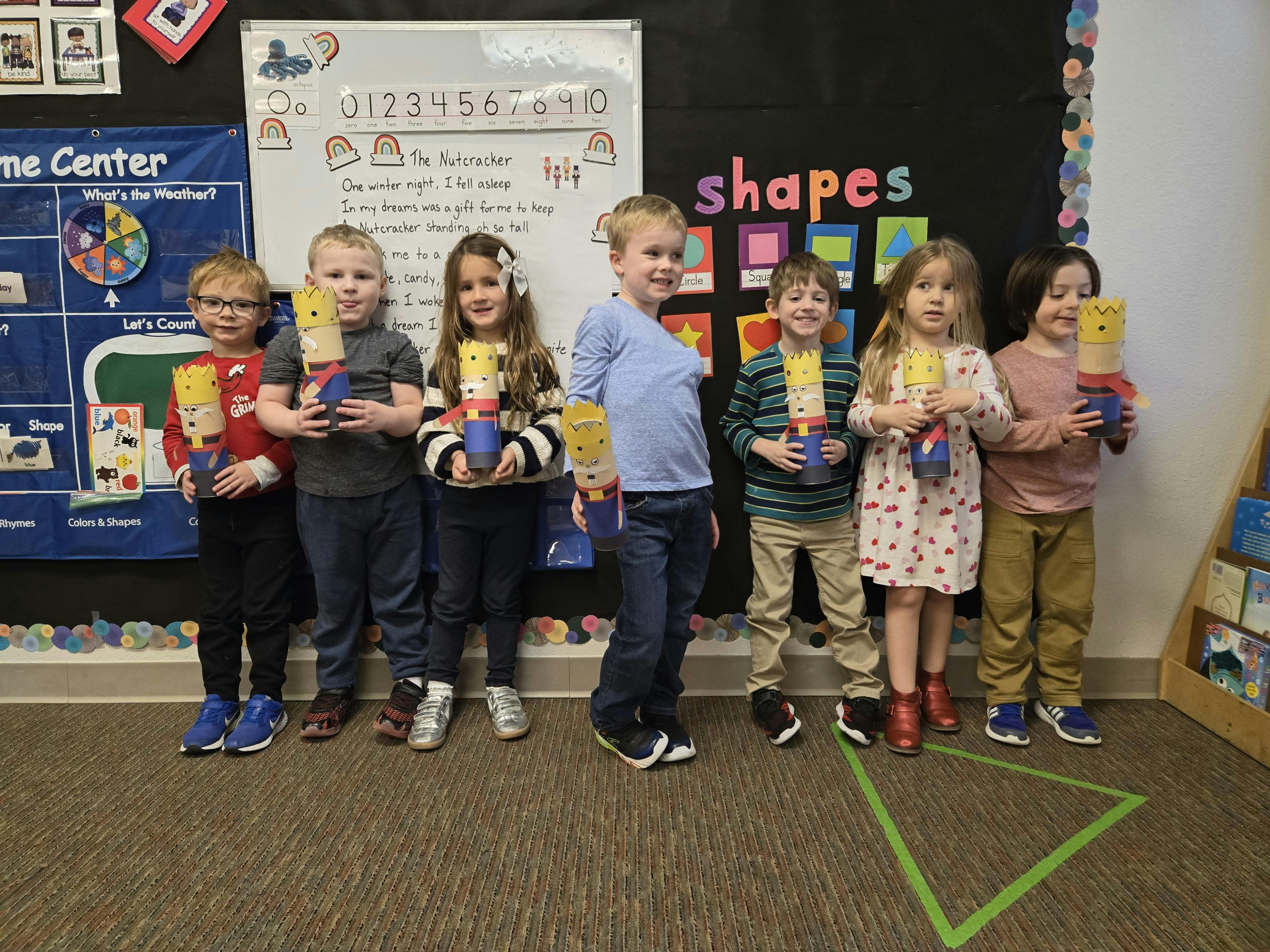 Group of children holding handmade nutcracker dolls in a classroom