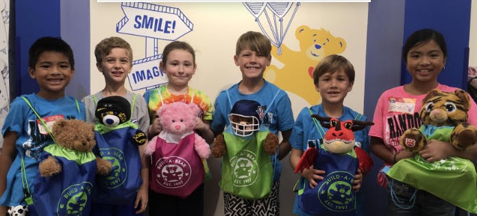 Six children holding stuffed animals in bags