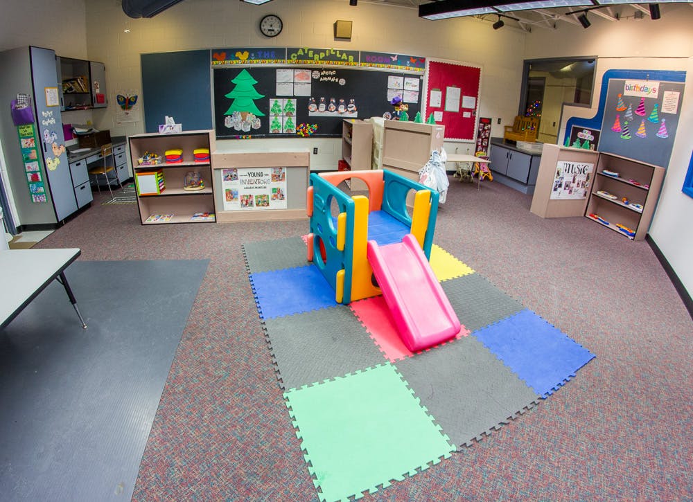 Indoor play structure with a pink slide on colorful foam mats in a classroom