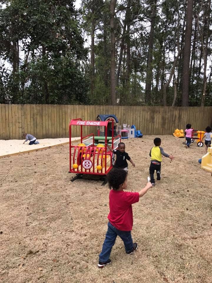 Children playing in a sandy outdoor area with play equipment