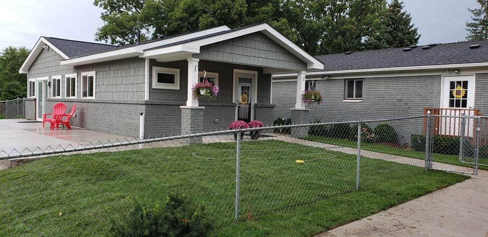 Two gray houses with white trim and a chain link fence