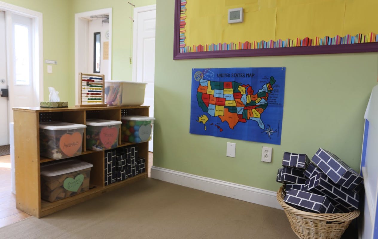 Classroom with a wooden shelf, map of the US, and a basket of blocks