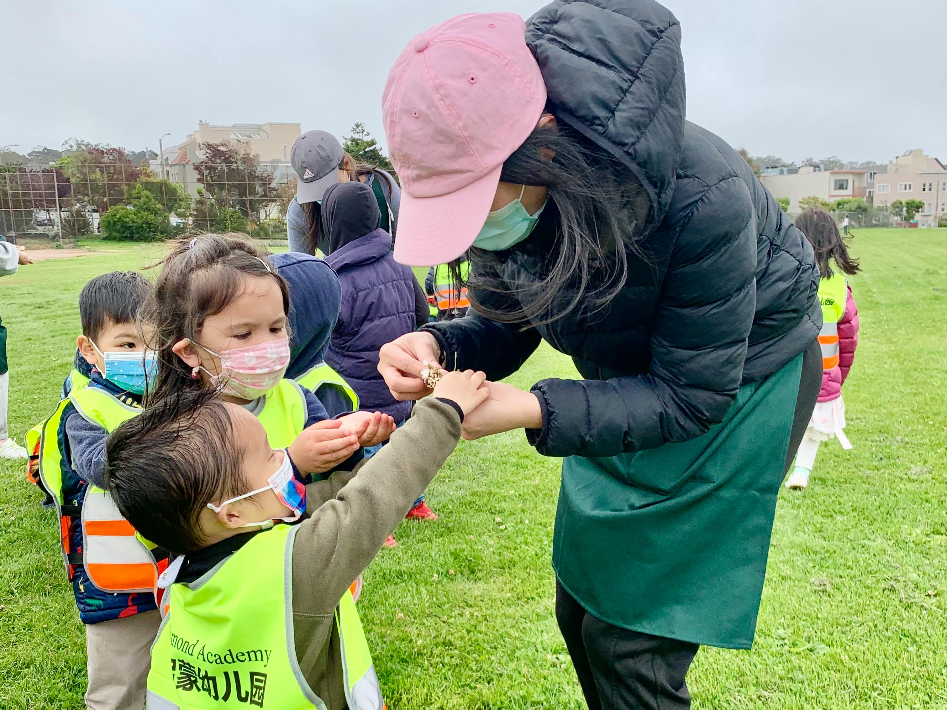 Adult and children in masks interacting outdoors
