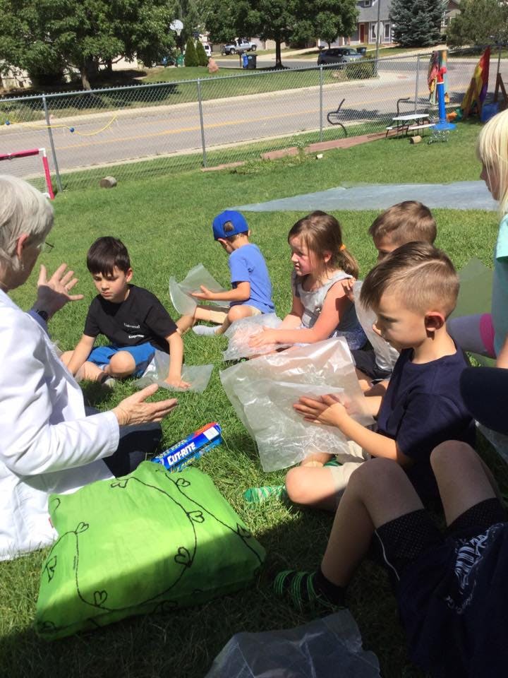 Adult and children sitting on grass with plastic bags