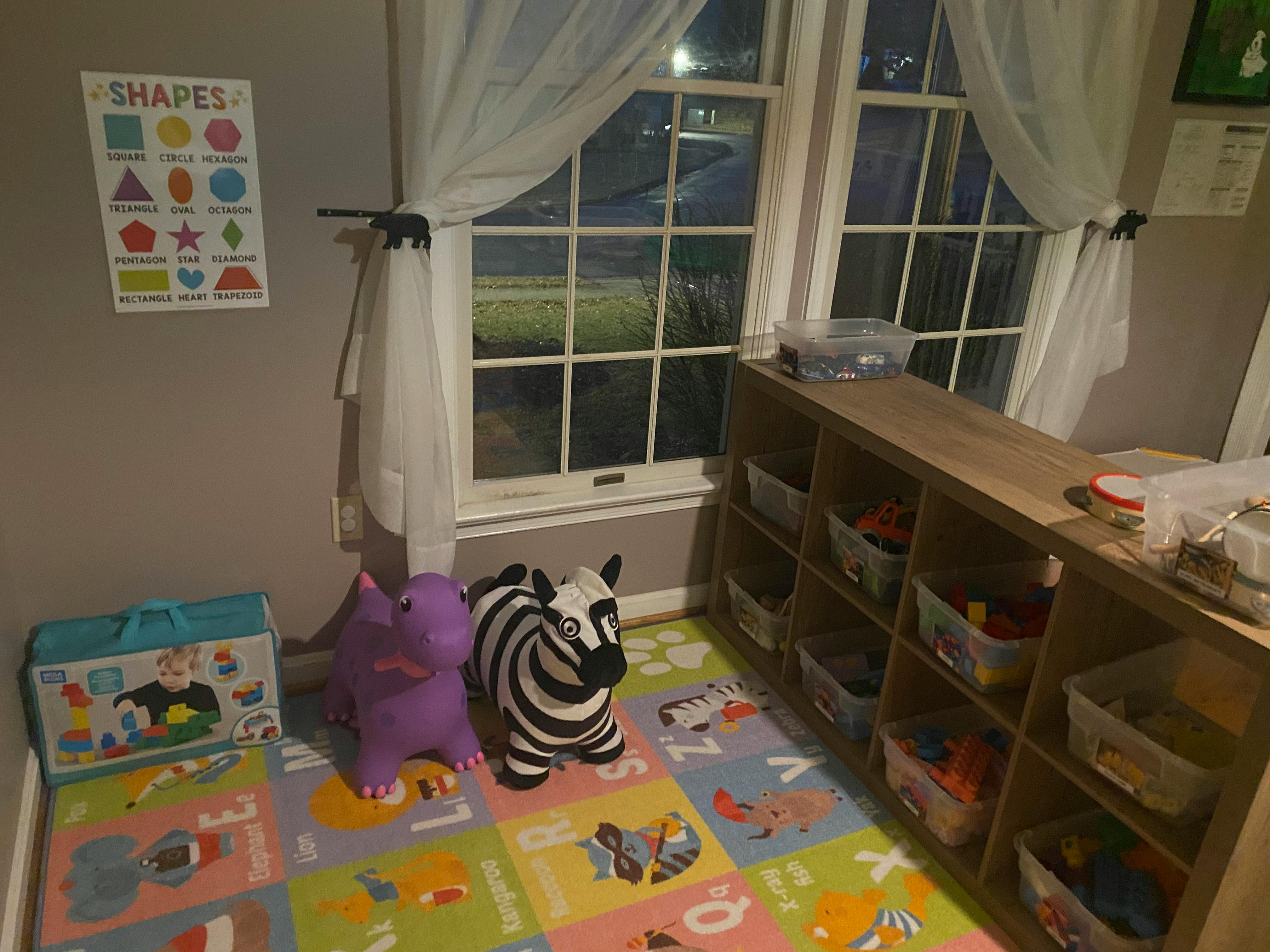 Playroom with toys, a colorful mat, and a window