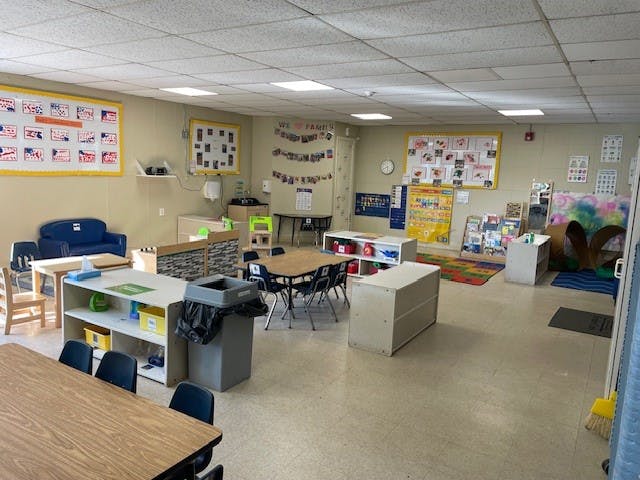 Empty classroom with tables, chairs, and learning materials