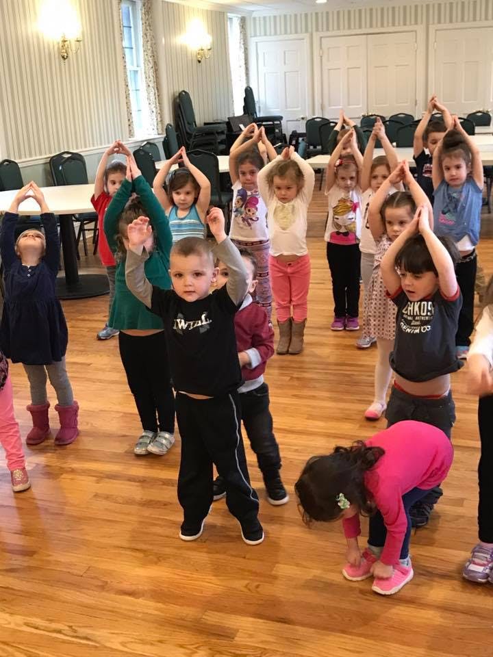 Group of children raising their arms above their heads in a room