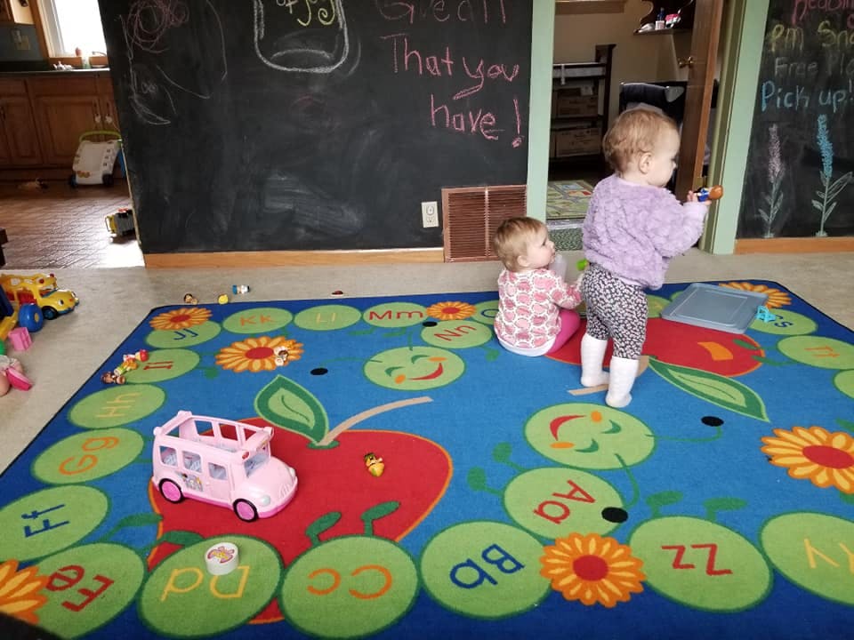 Two children playing on a colorful alphabet rug