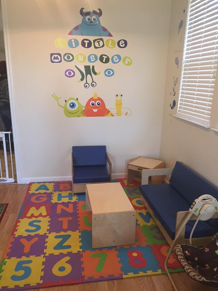 Playroom with monster wall decals, alphabet floor mat, and blue seating