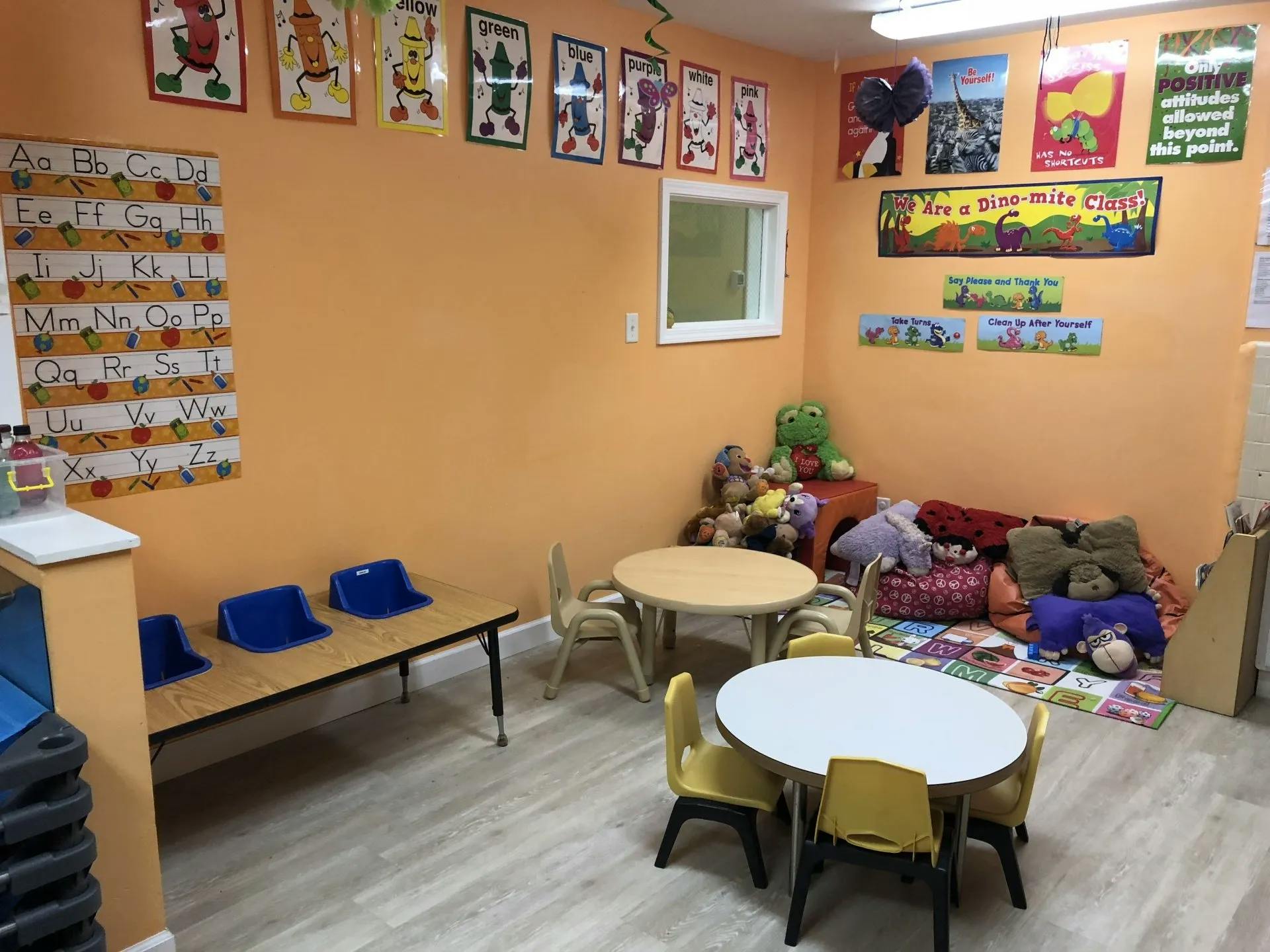 Children's classroom with small tables and chairs, alphabet chart, and toys
