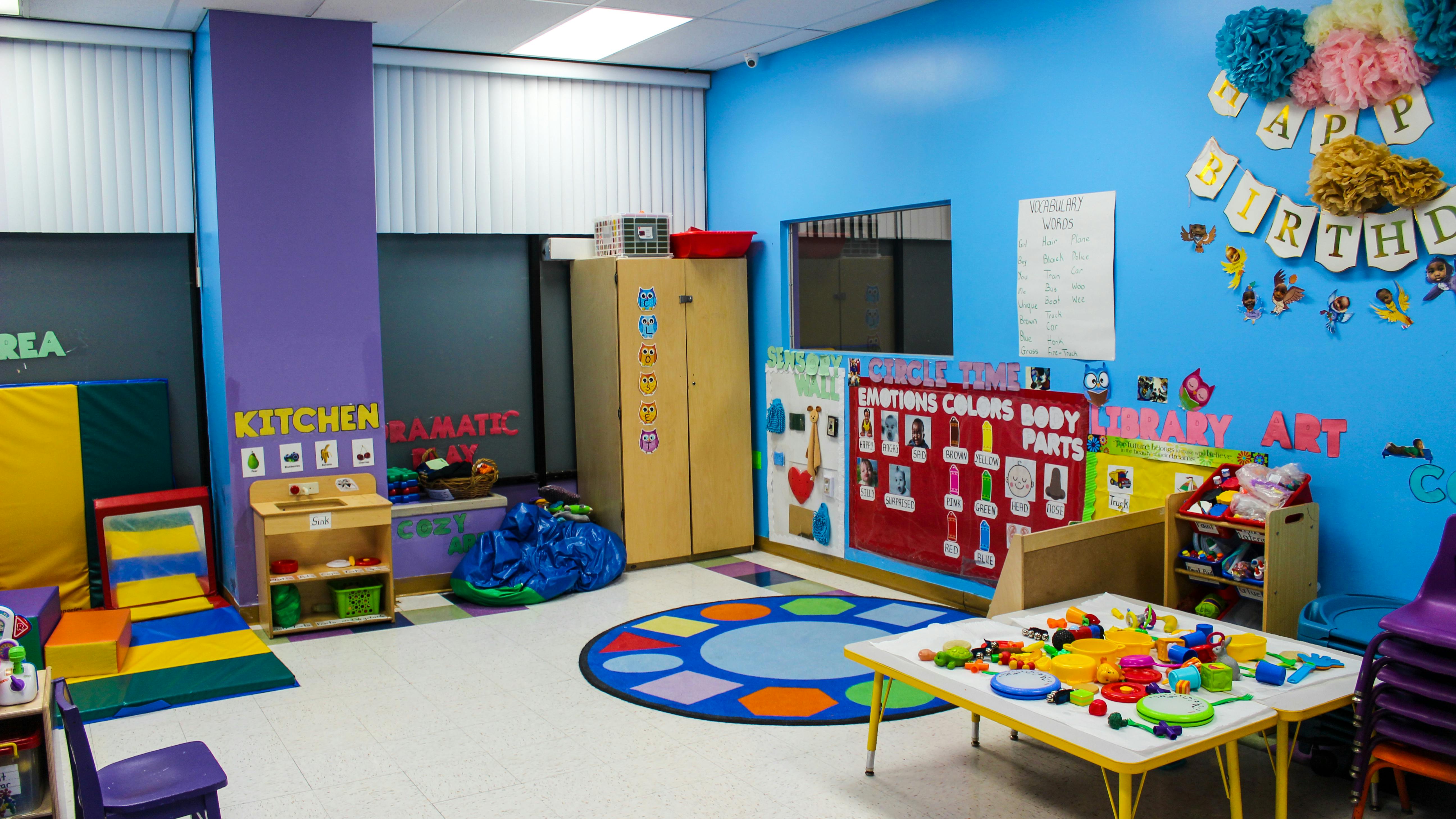 Colorful classroom with play kitchen, rug, and activity table