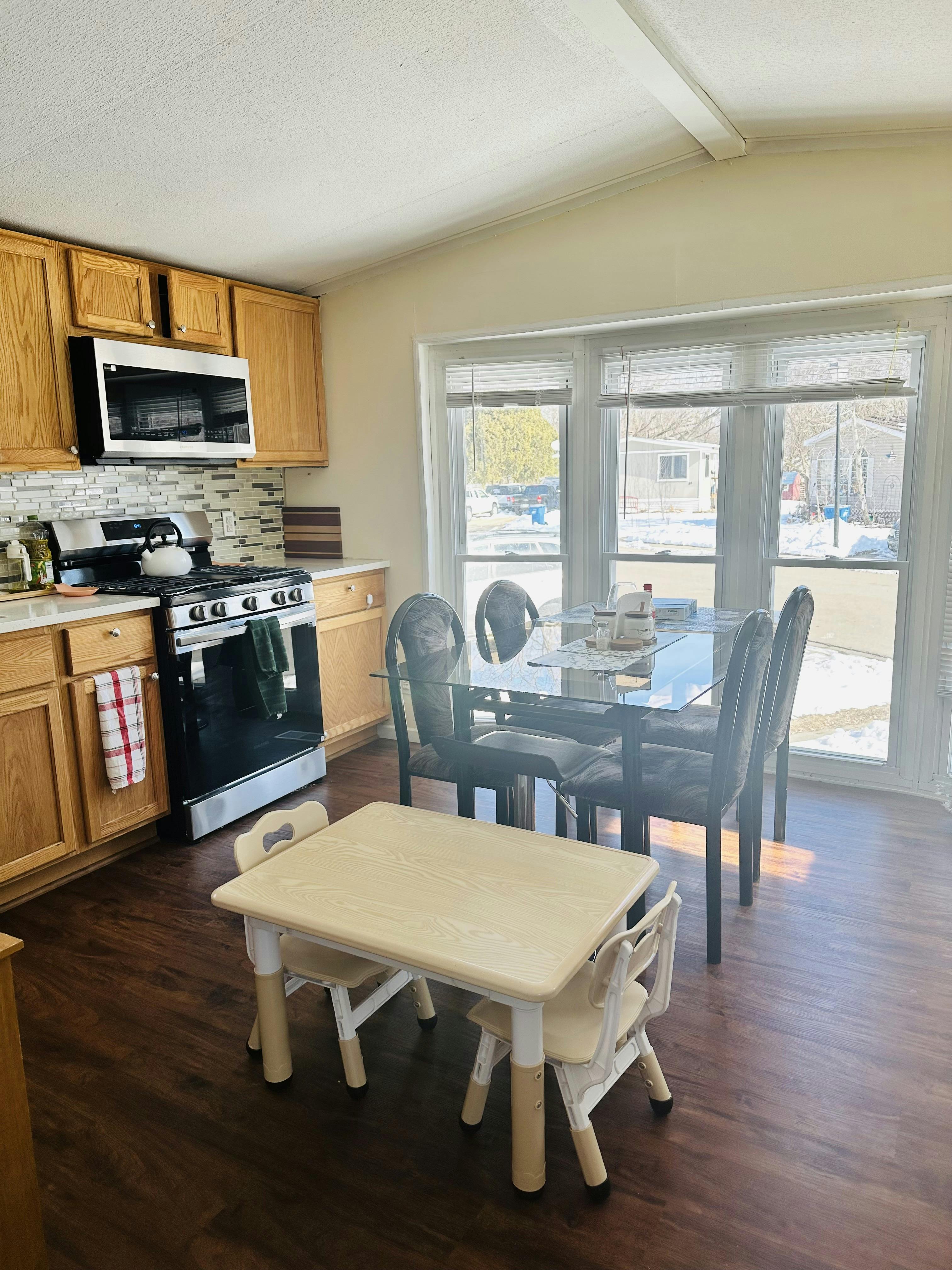 Kitchen area with wooden cabinets, a stove, and two dining tables