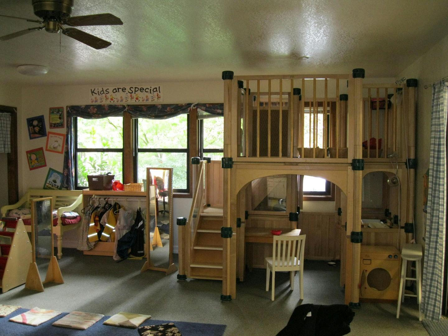 Indoor play structure with stairs, railings, and a small desk area underneath