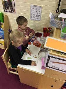 Two children sitting at a table doing crafts