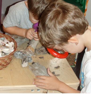 Two children looking closely at objects on a table