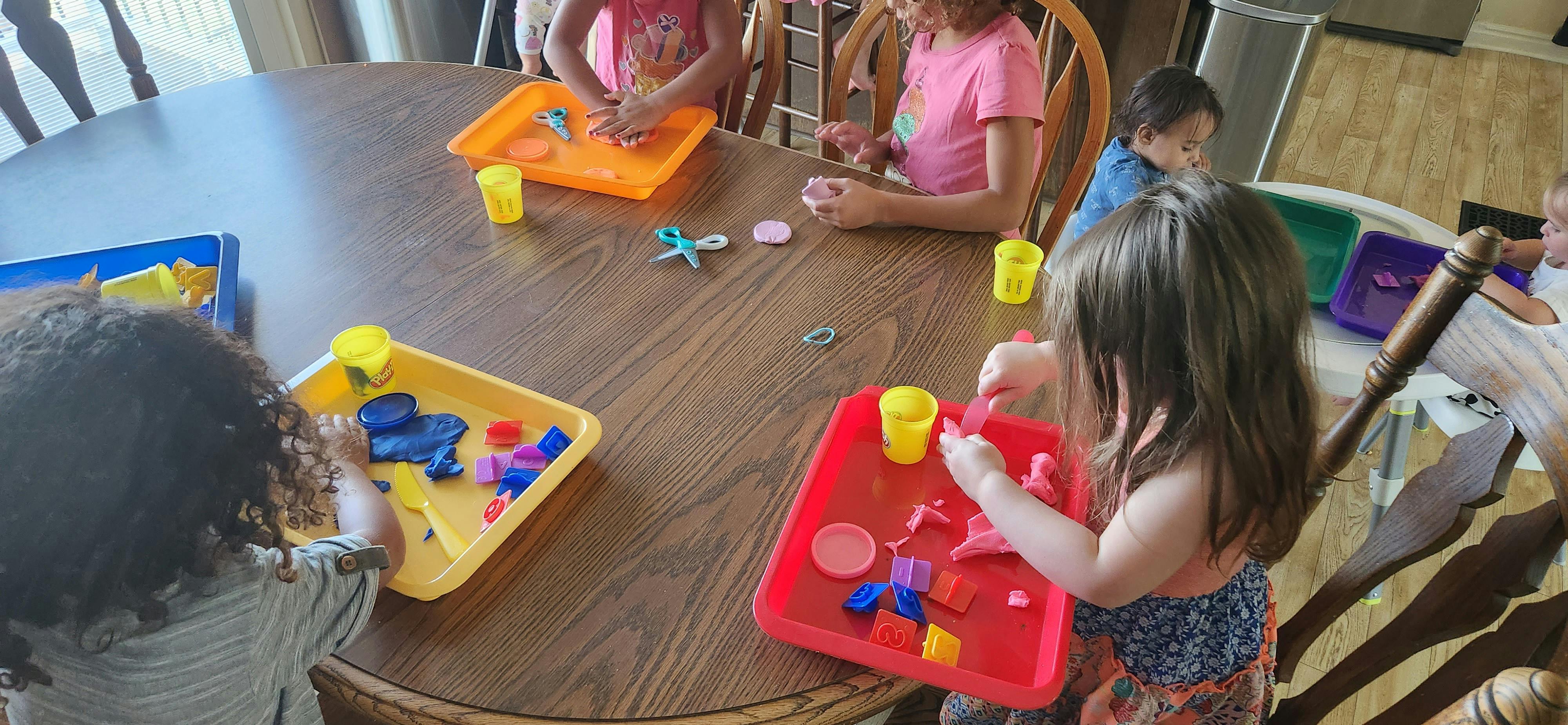 Children playing with colorful trays and toys at a table
