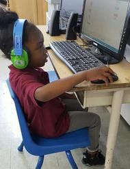 Child wearing headphones and using a computer mouse