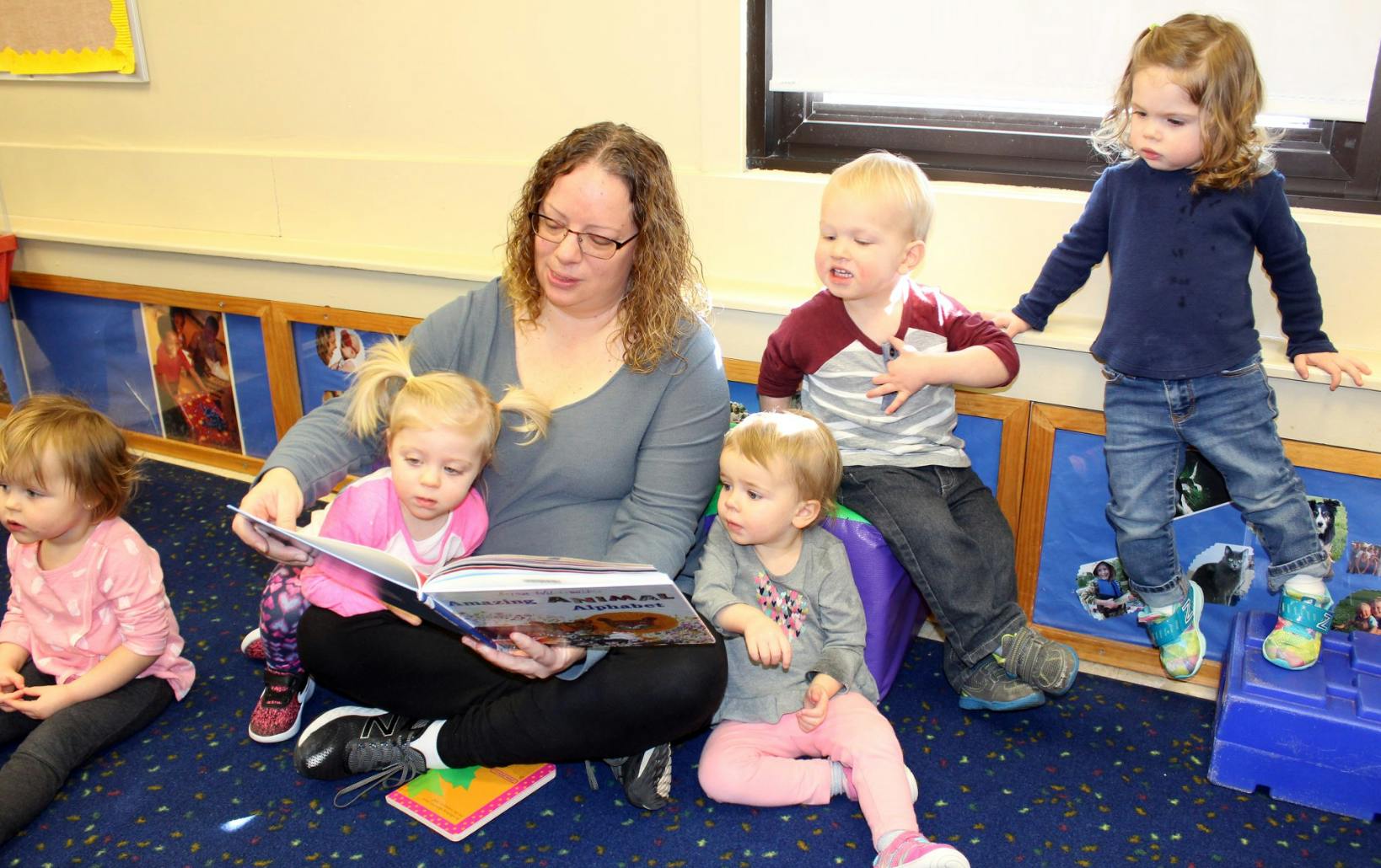 Person reading a book to multiple children in a classroom