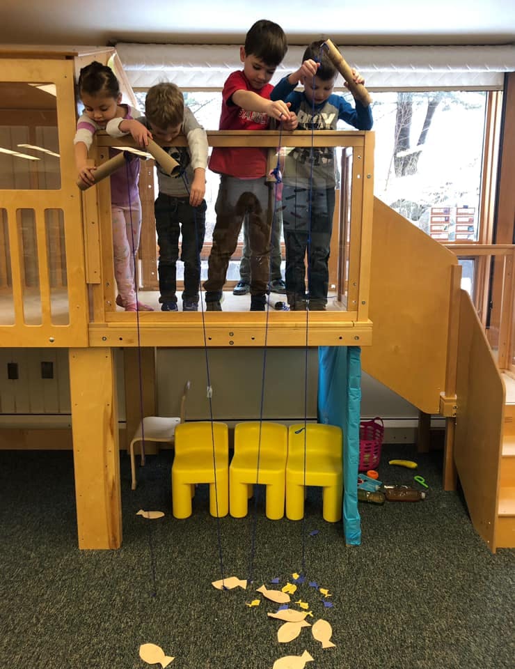 Children playing with cardboard tubes on a wooden play structure