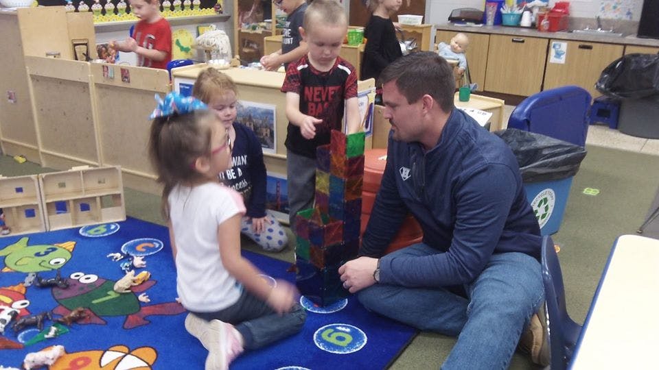 Adult and children playing with blocks in a classroom