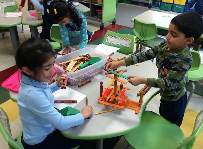 Two children playing with building blocks at a table in a classroom