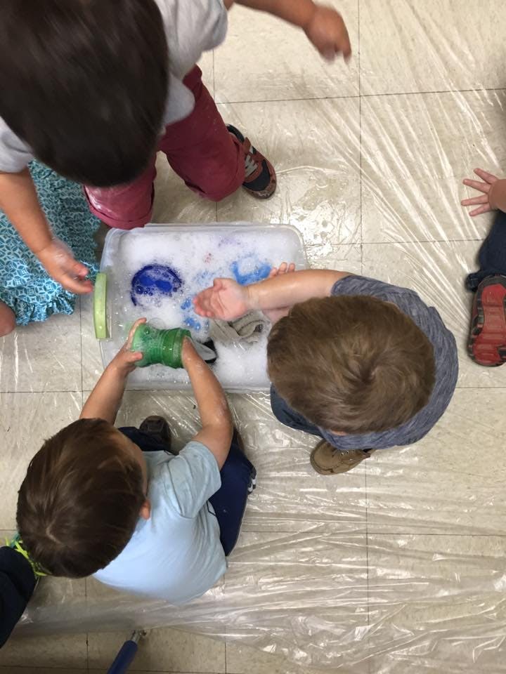 Children playing with soapy water in a plastic bin