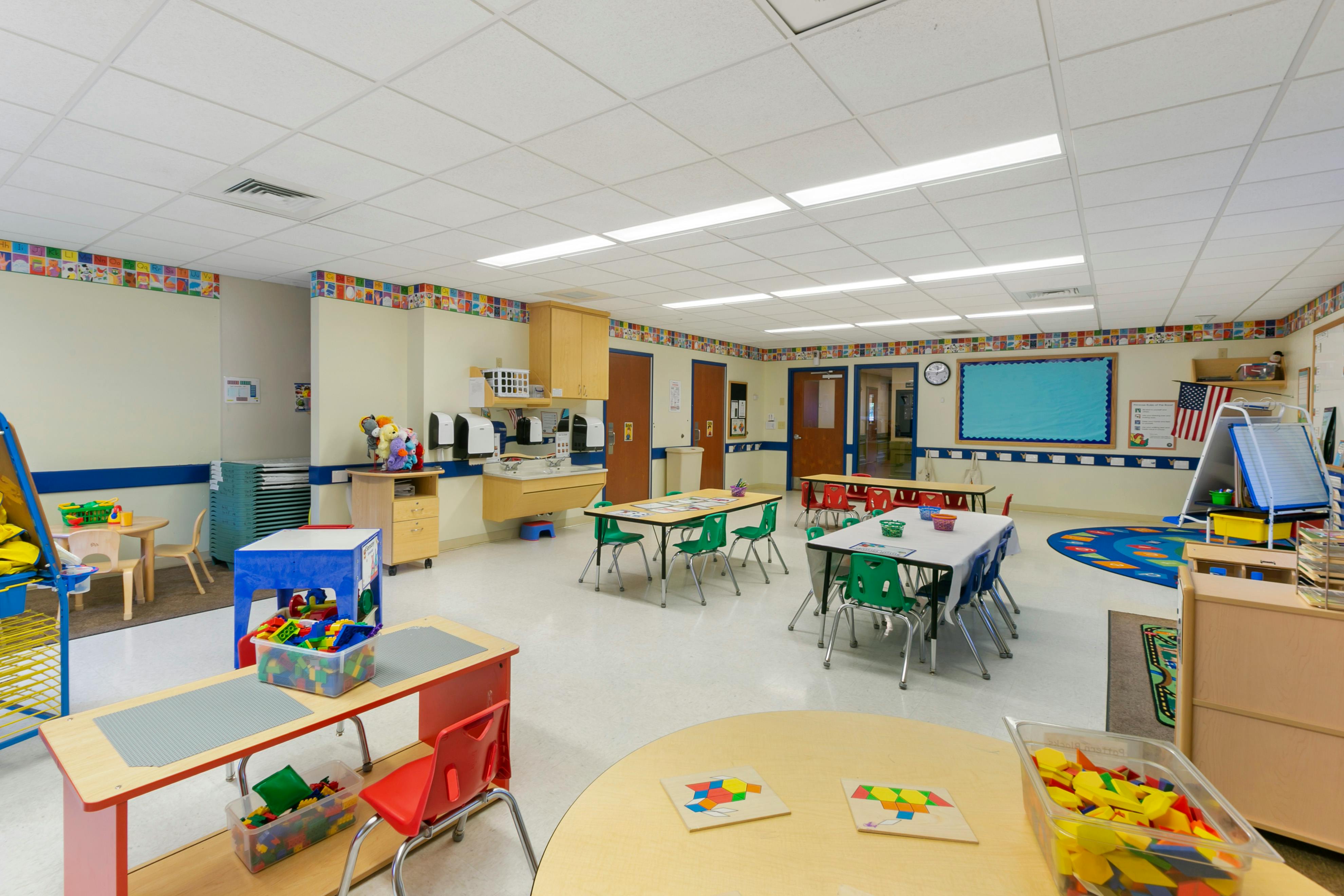 A colorful and brightly lit classroom with tables, chairs, and learning materials