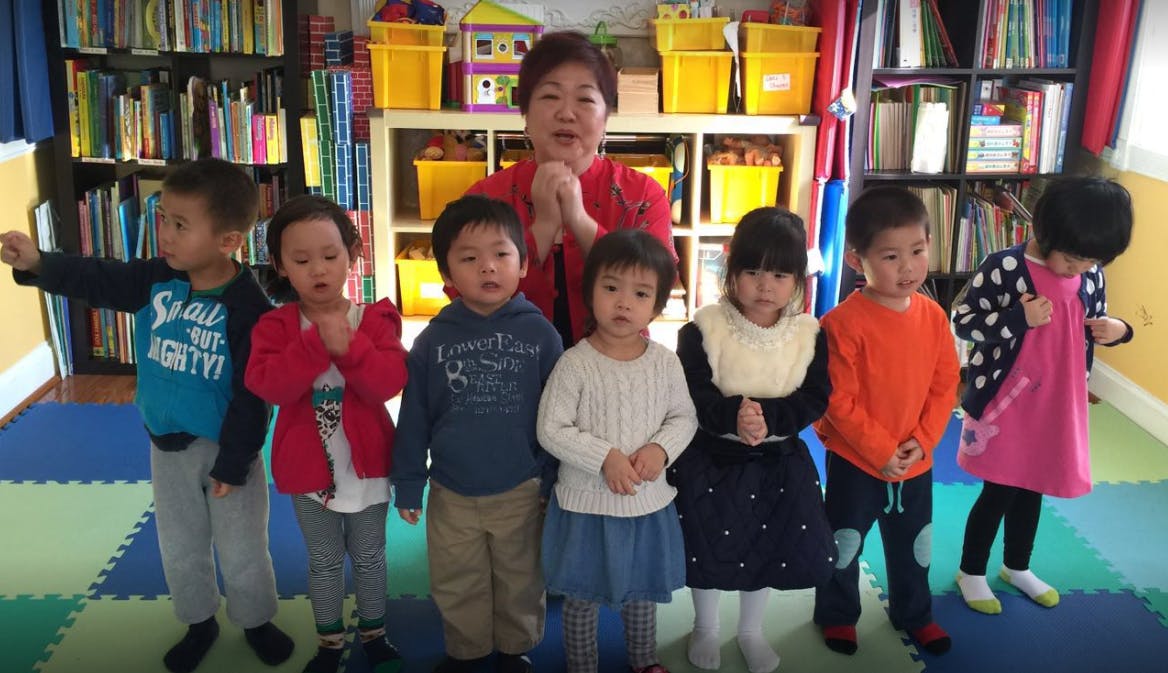 Adult and multiple children standing indoors