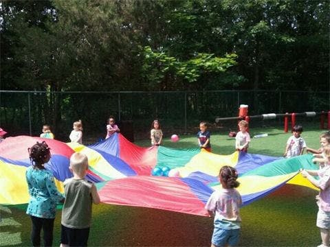 Children playing with a colorful parachute outdoors