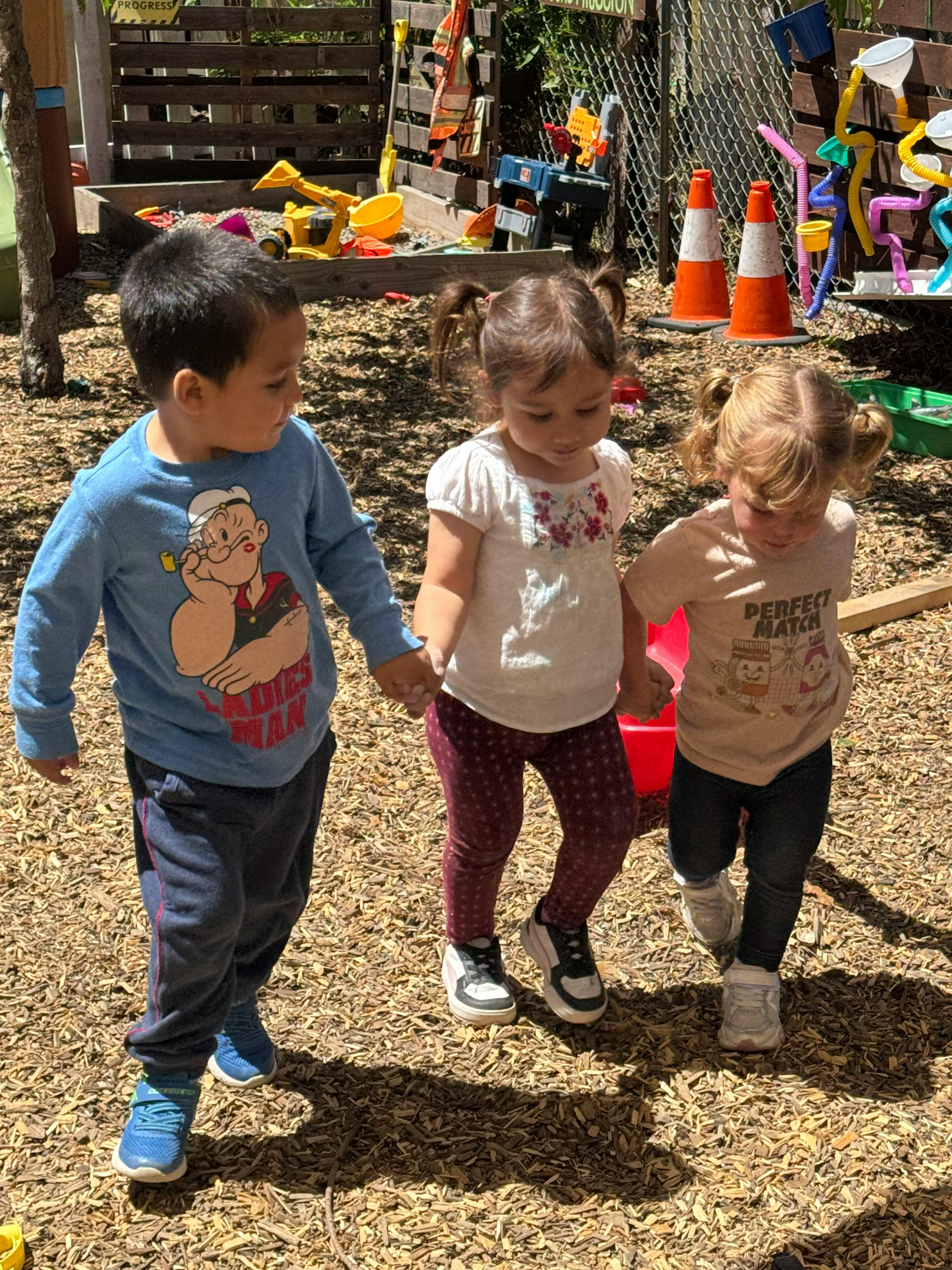 Three children holding hands and walking outdoors