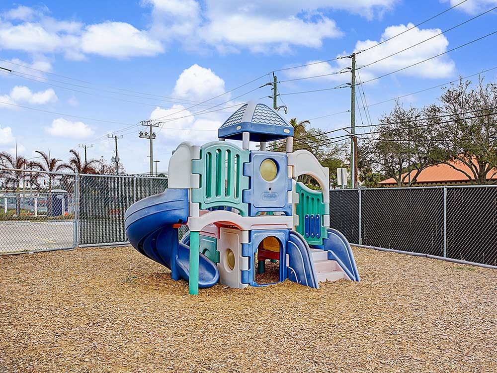 A colorful playground structure with slides and climbing areas on wood chips
