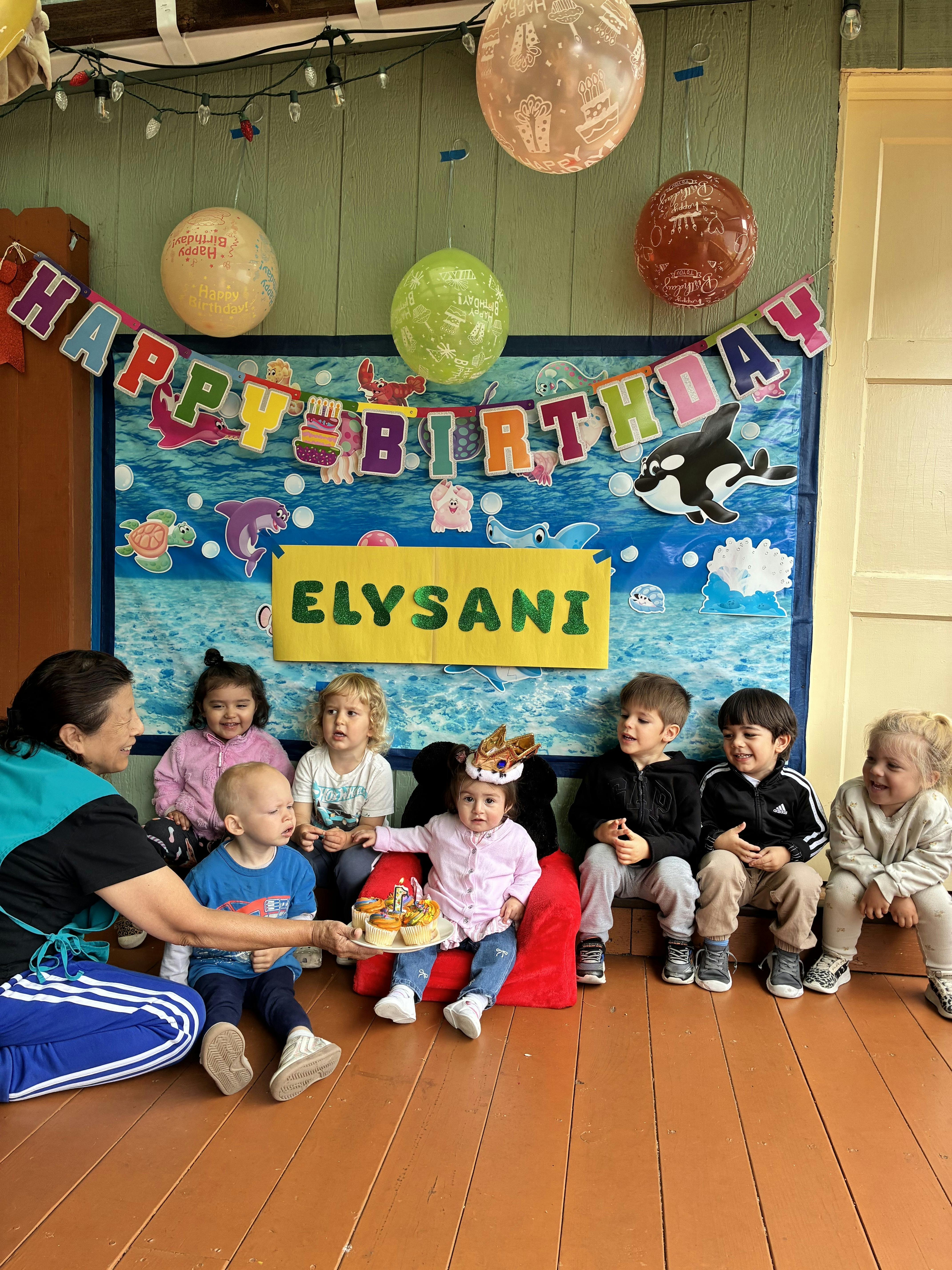 A person serving cupcakes to a group of children at a first birthday party