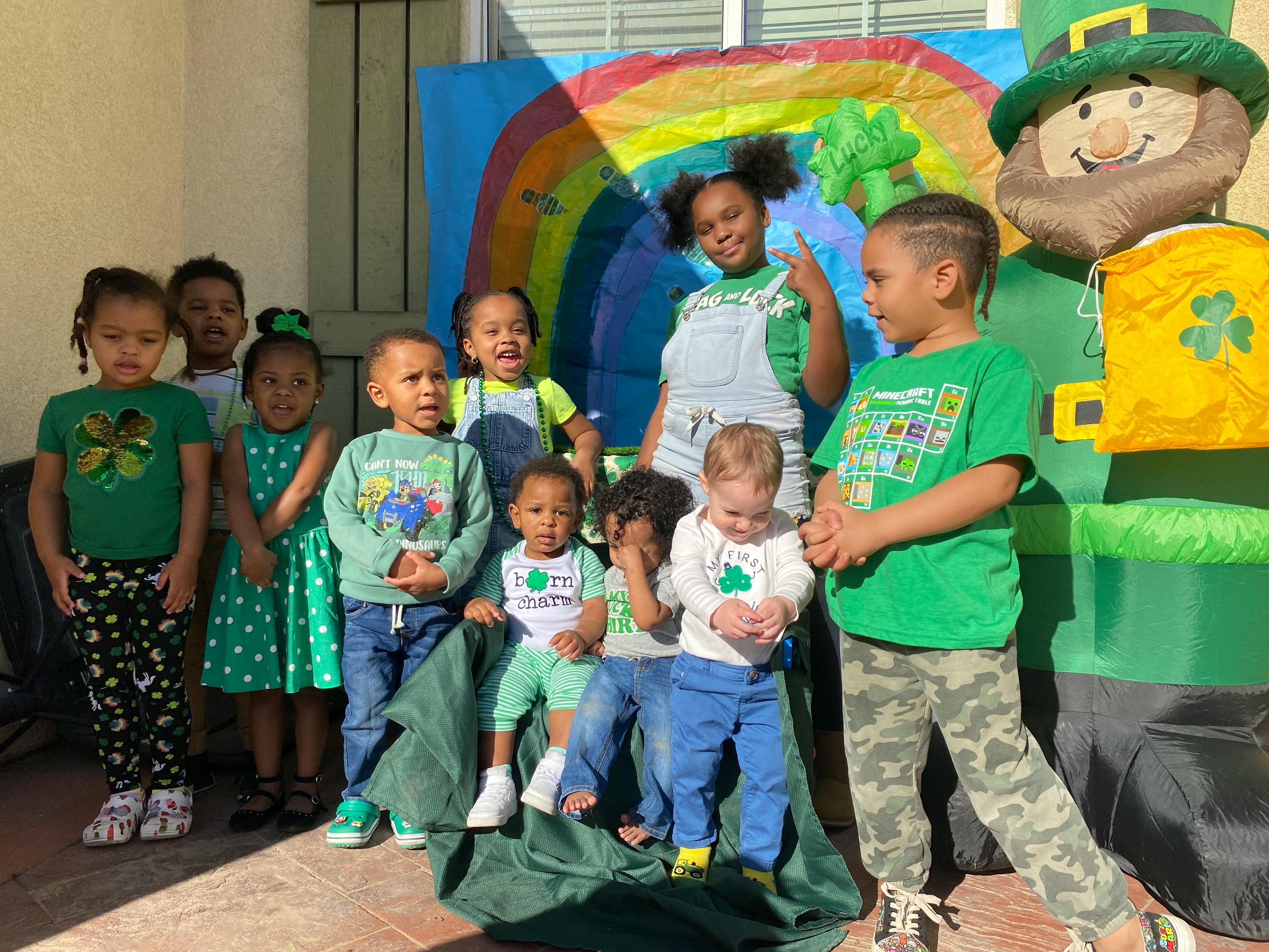 Group of children posing with a large inflatable leprechaun and rainbow