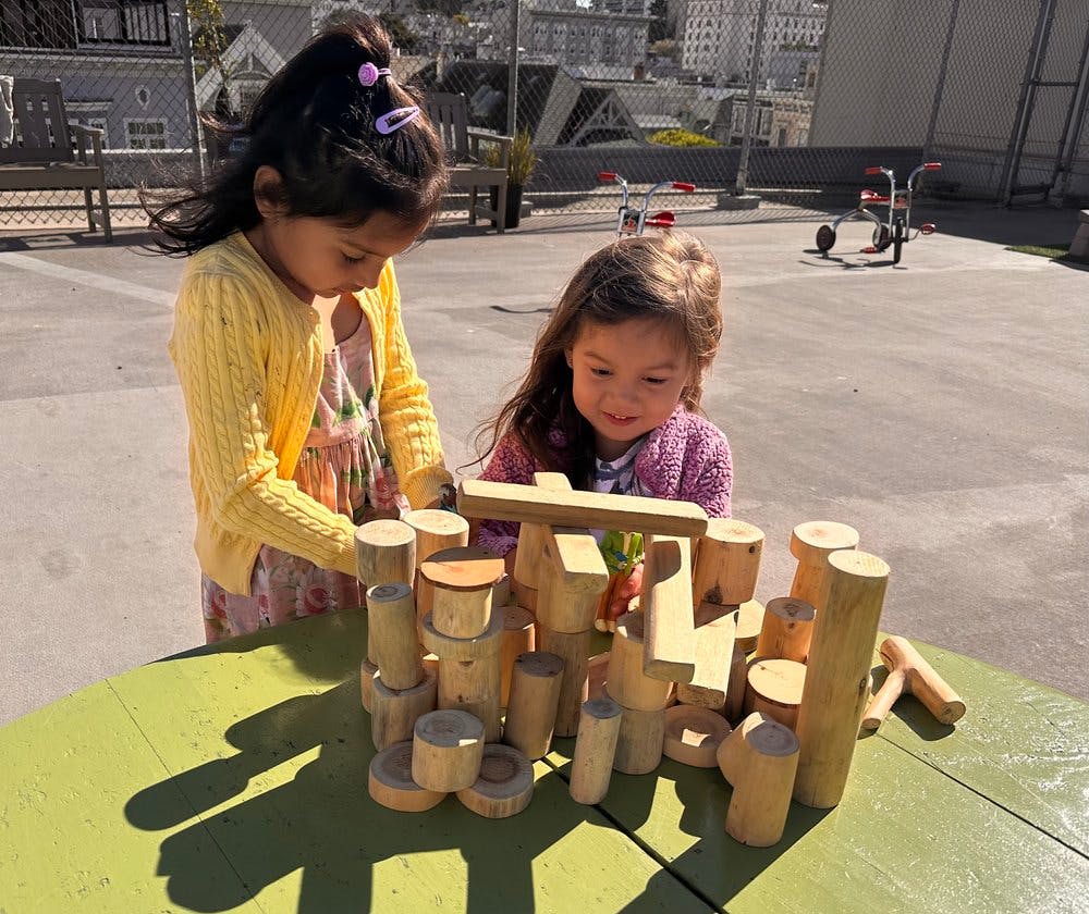 Two children playing with wooden blocks on a table
