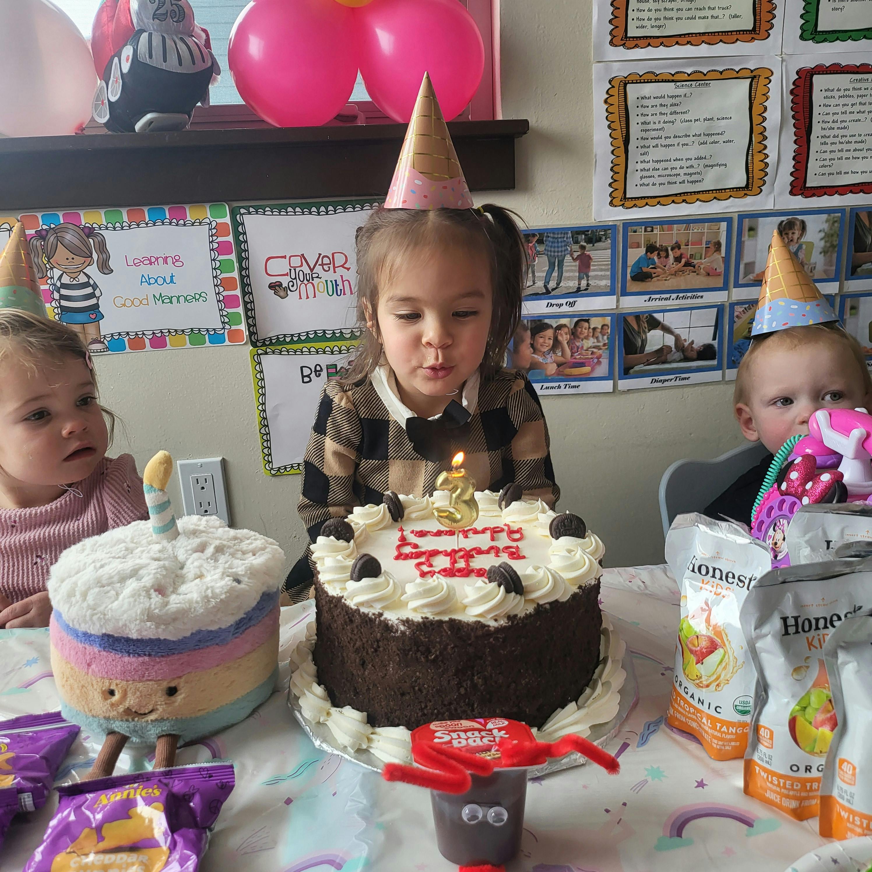 Child in party hat blowing out a candle on a birthday cake