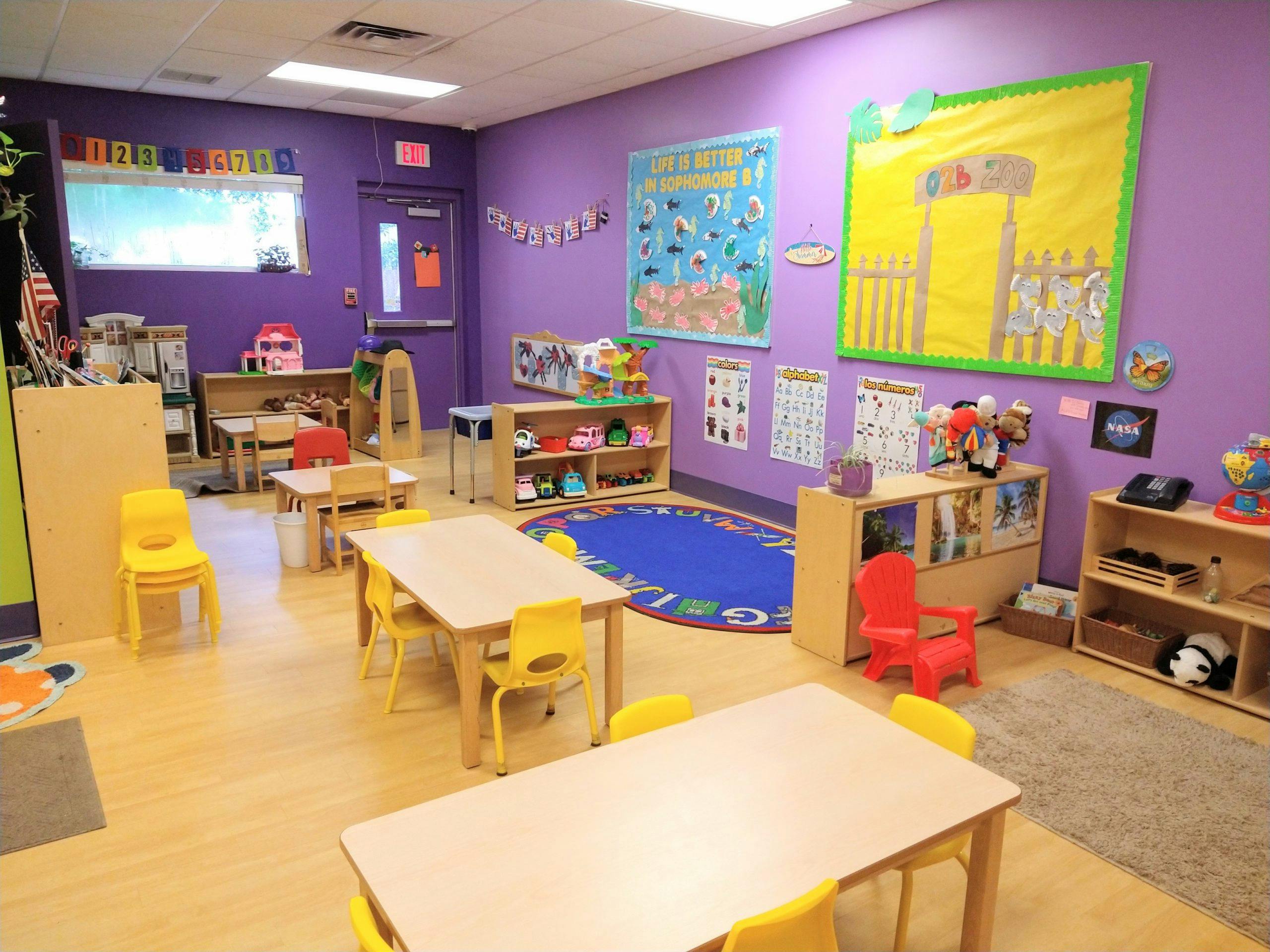 An empty early childhood classroom with colorful decor and small tables and chairs