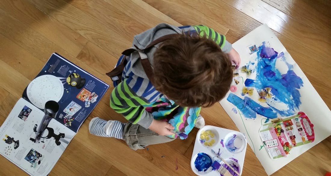 Child painting on paper on the floor
