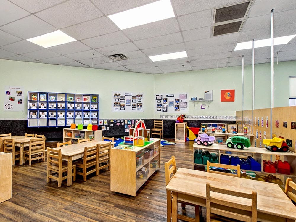 Classroom with small wooden tables and chairs, toys, and learning materials