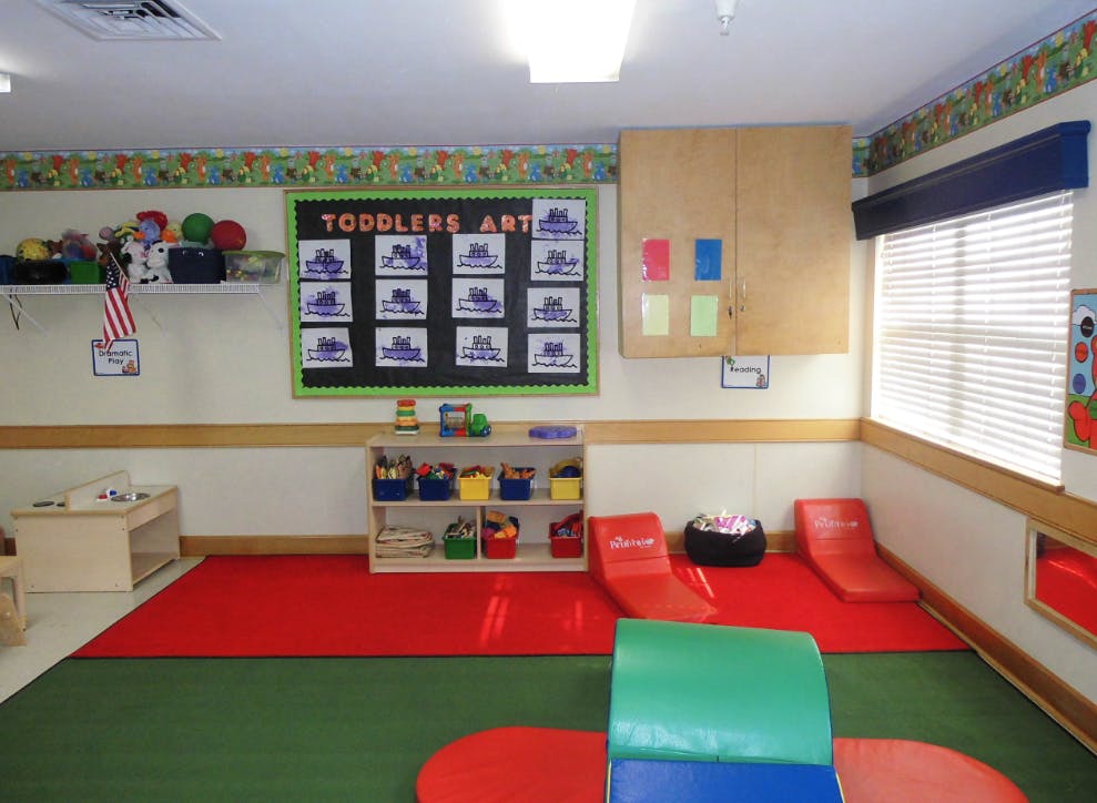 Toddler classroom with a "Toddlers Art" board and play mats