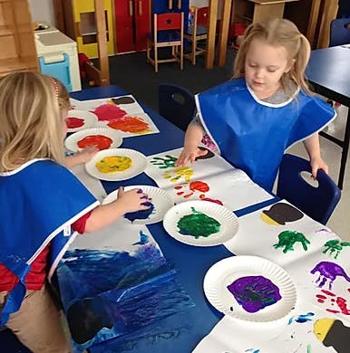 Two children finger painting at a table