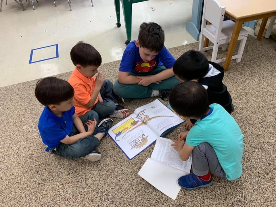 Five children sitting on the floor looking at books