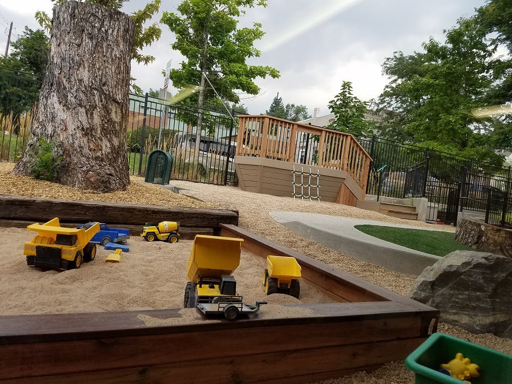Sandbox with toy trucks and a playground in the background