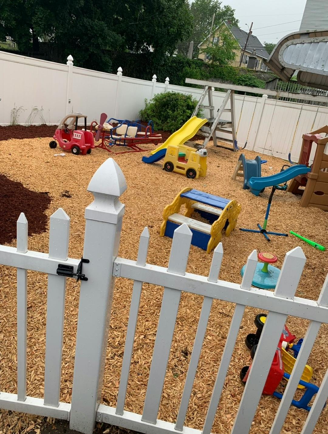 Playground with various play equipment and a white picket fence
