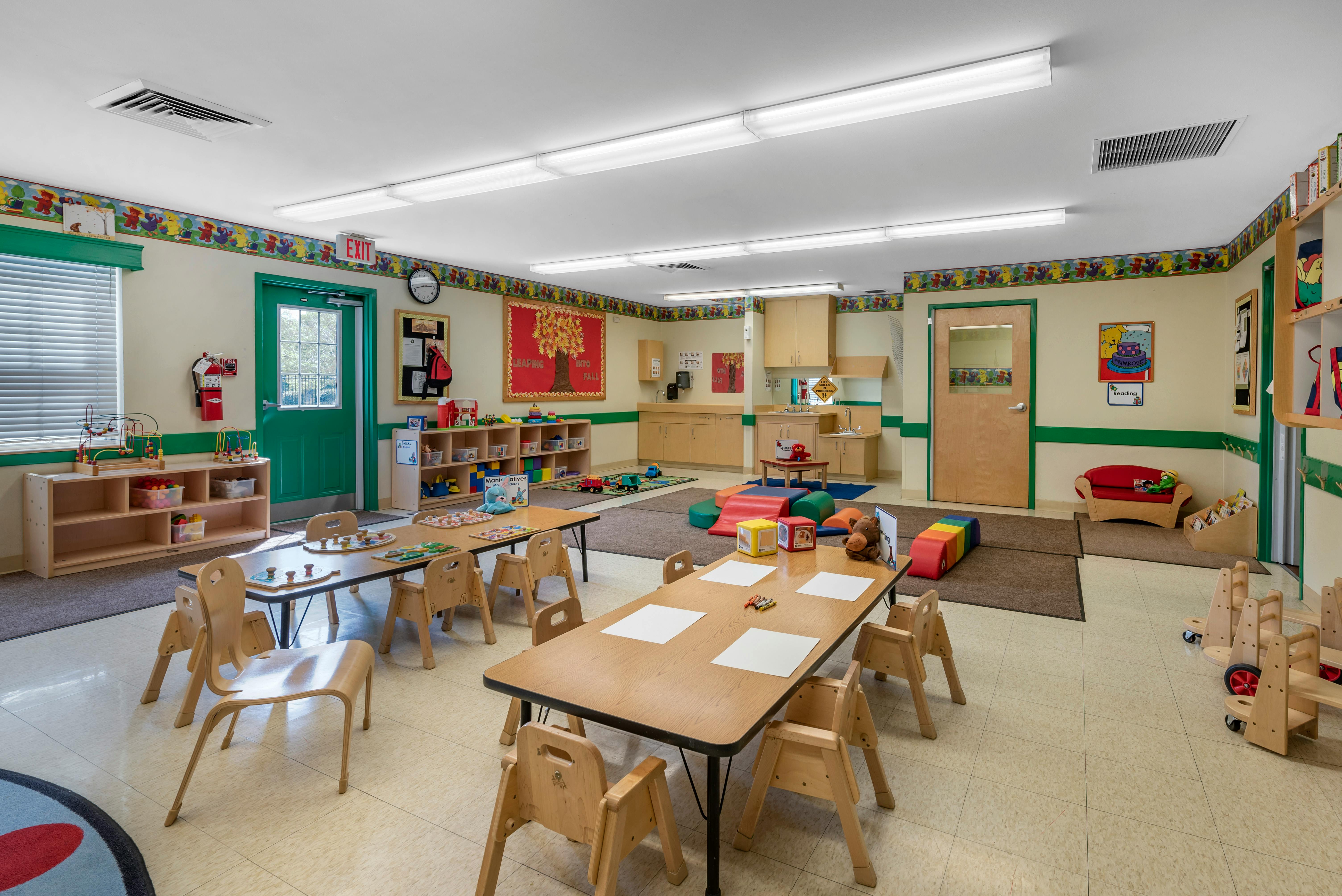 Classroom with child-sized tables and chairs, play mats, and learning materials