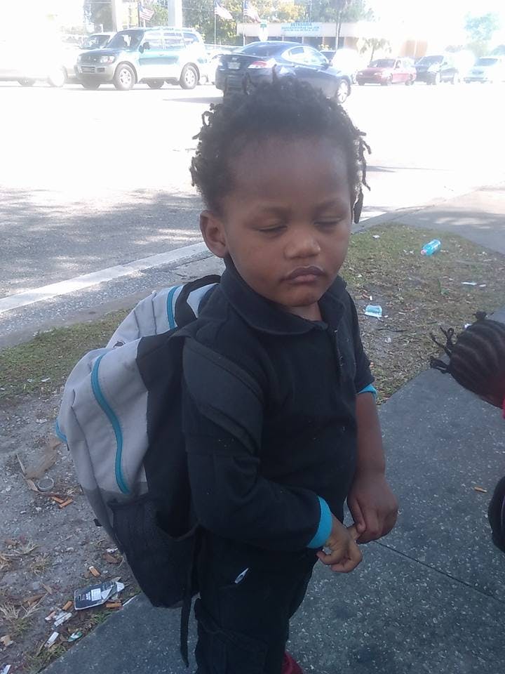 Child with closed eyes wearing a backpack